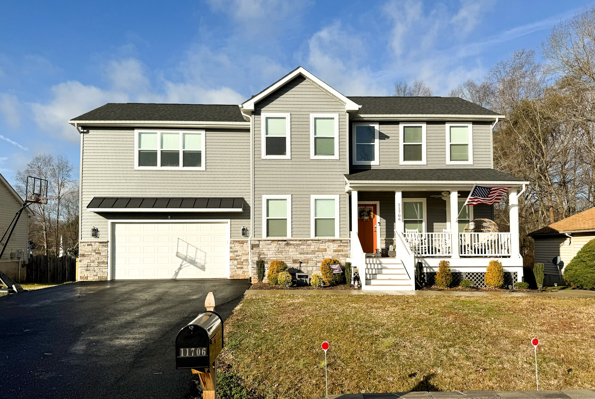 Two‑story gray house with a front porch, white trim, and an attached garage, set against a blue sky belonging to Sponsored Residential Providers Crystal and Christopher Cameron in Fredericksburg, Virginia.