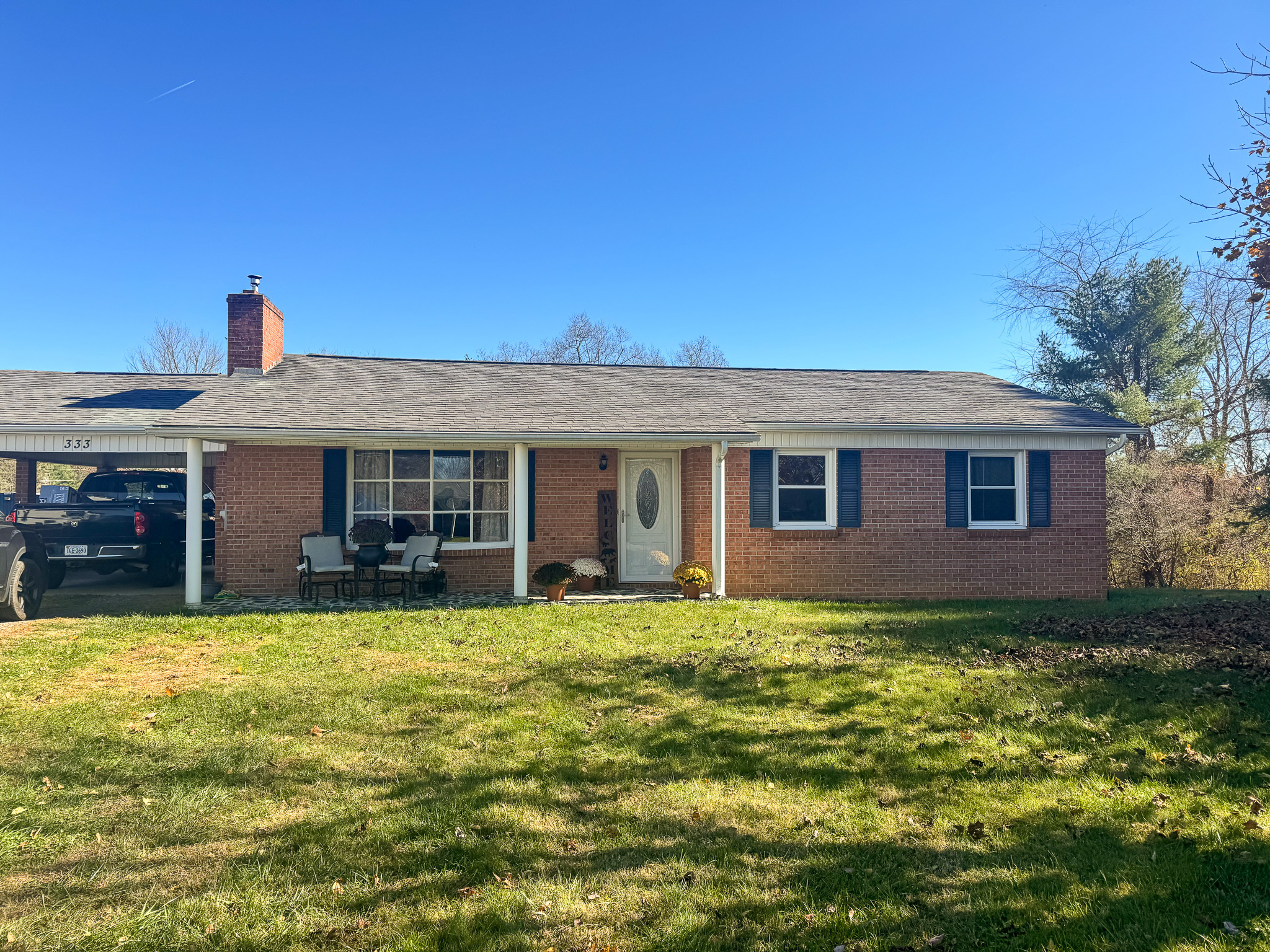 A one‑story brick house with a covered carport on the left, a white front door, black shutters, and a grassy front yard belonging to Sponsored Residential Provider Pamela Hill in Austinville, Virginia.