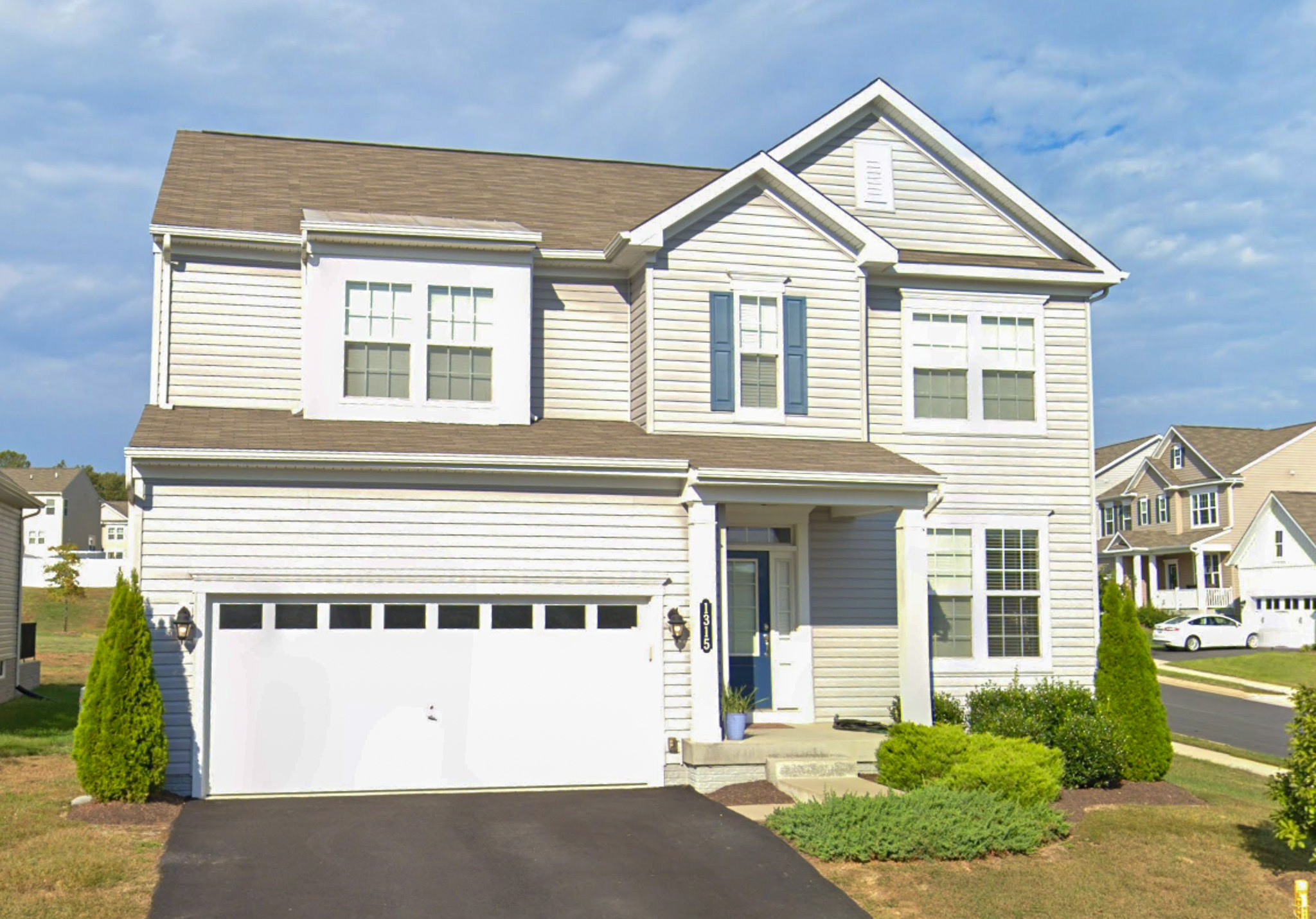 A two‑story suburban house with a white two‑car garage, light‑colored siding, green shutters, and a paved driveway, belonging to Torwon and Deljuan Mitchell in Fredericksburg, Virginia.