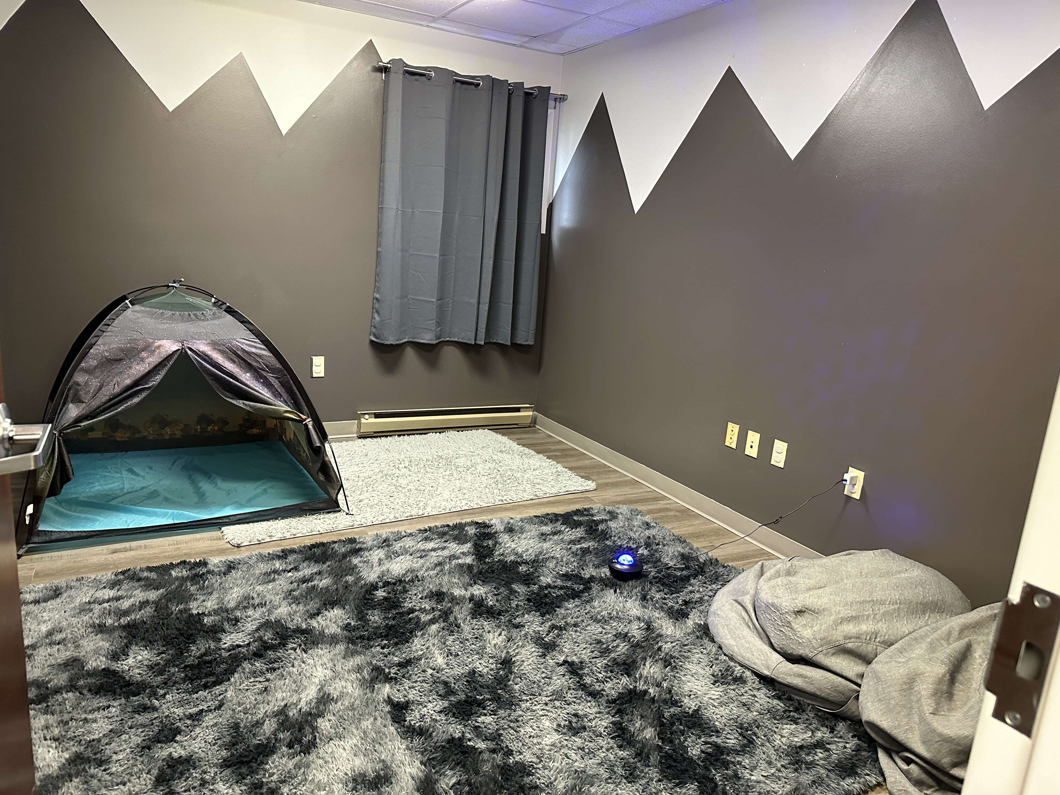Room in the Christiansburg ABA Center featuring a grey carpet, a small tent, and mountains painted on the walls