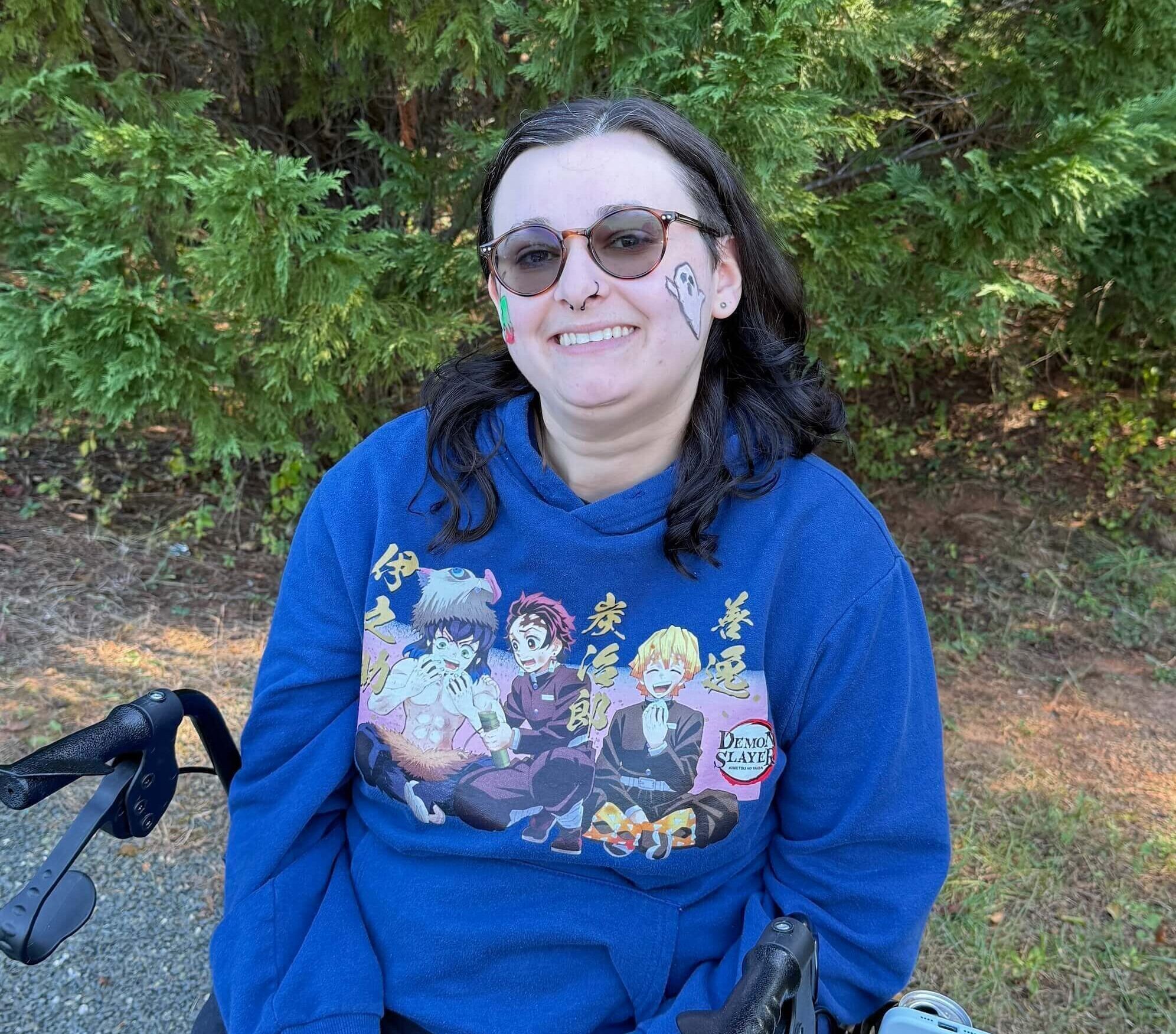 Woman sitting in a walker outside smiling into camera with sunglasses
