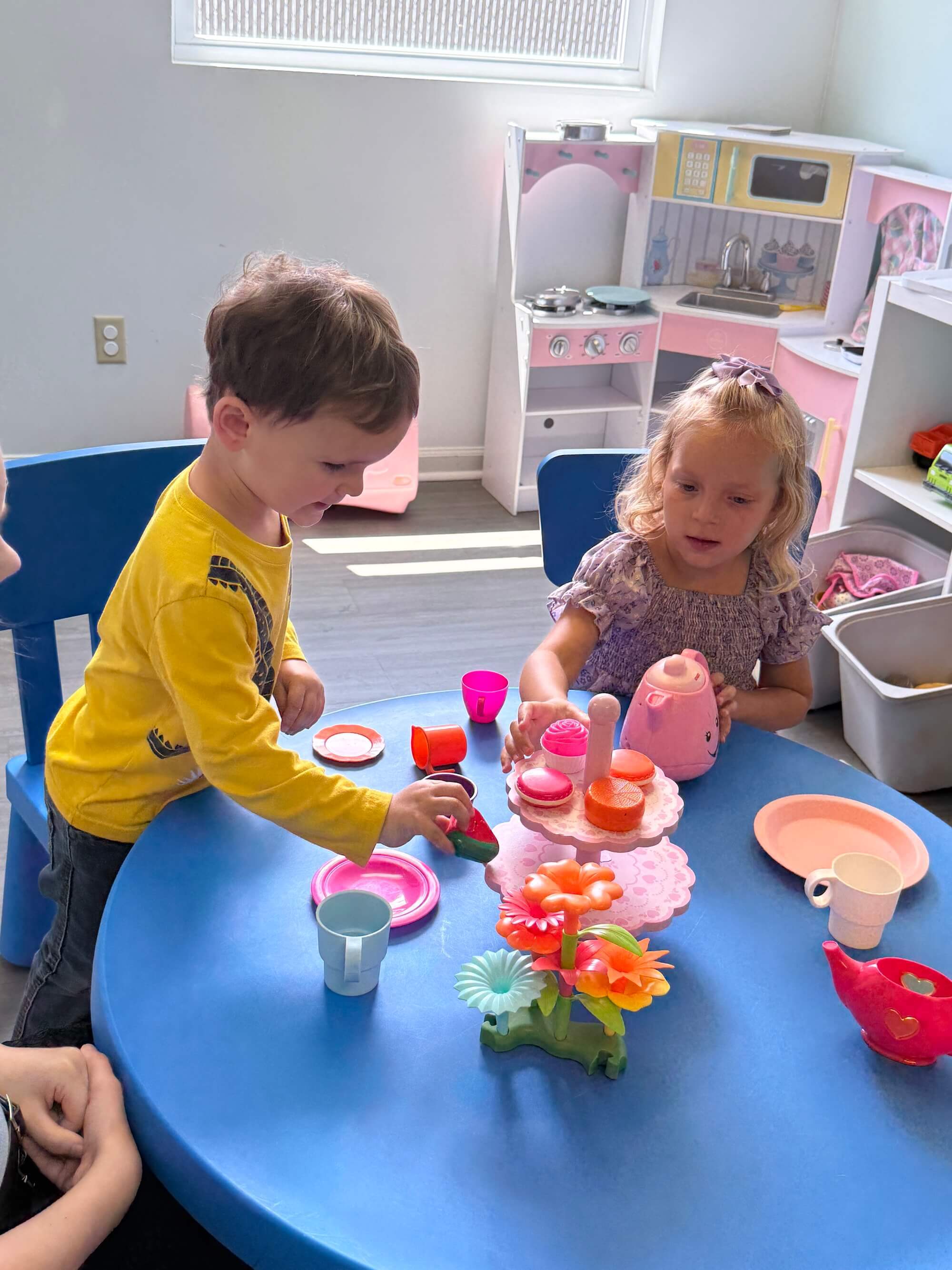 Two young children play with toys at a table in the ABA center