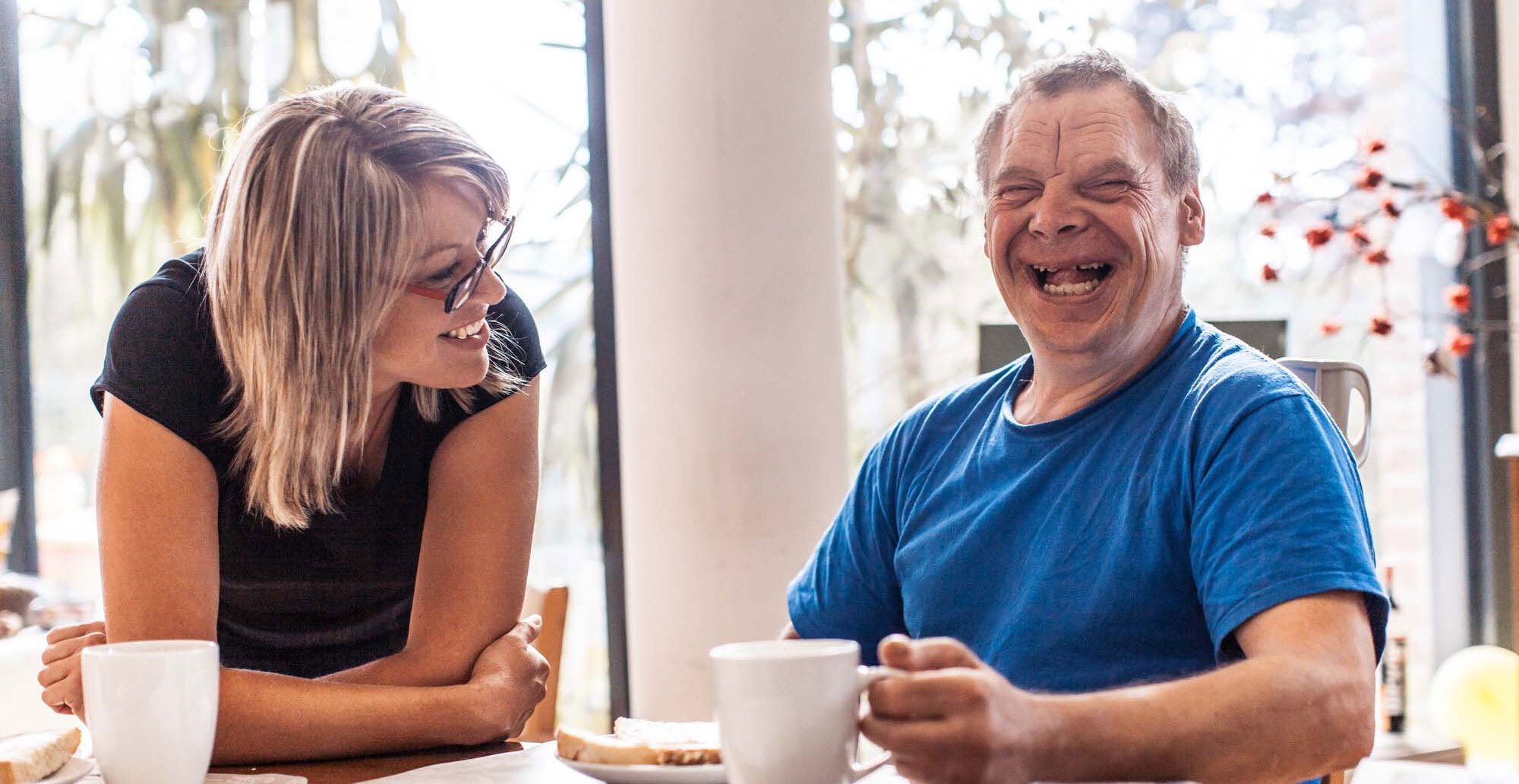Therapist and client sitting side by side share a laugh