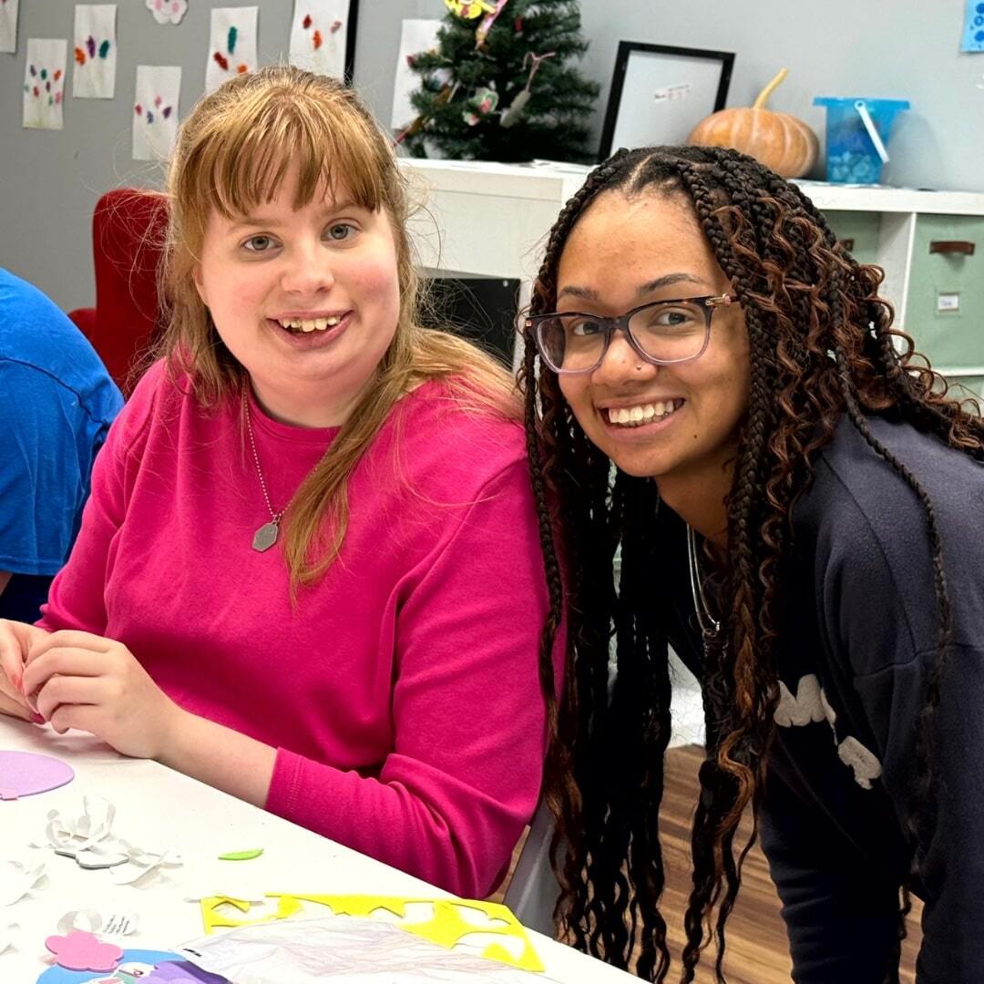 Recreational therapist and client pause an art project to smile at the camera