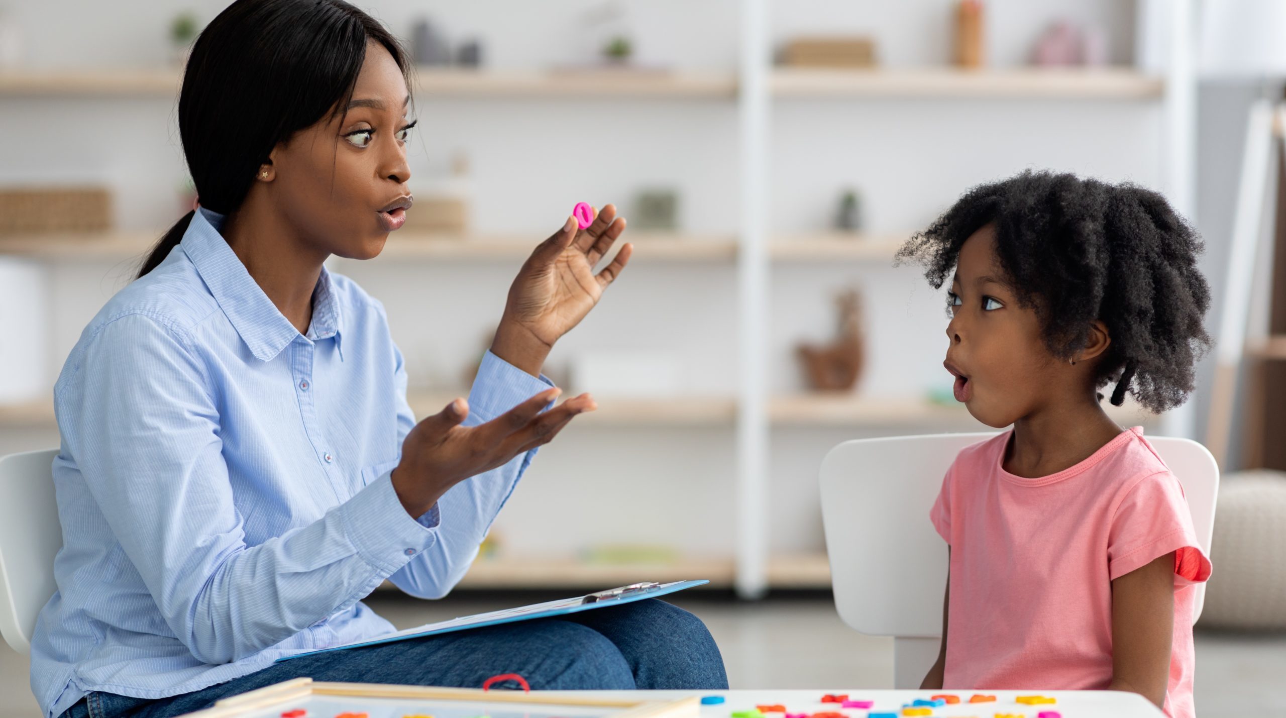 Speech therapist uses hand signals and expressive mouth shapes to teach a young girl